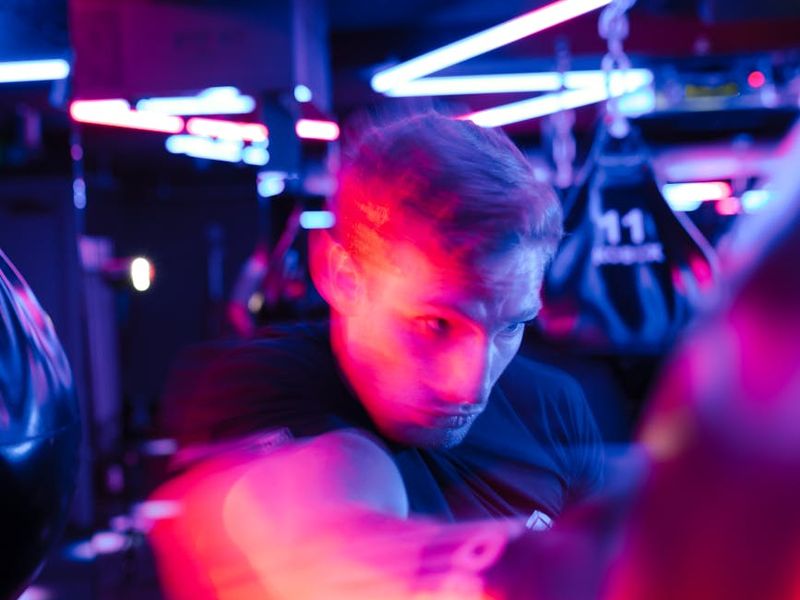 Man performing focused strength exercise with blue neon lighting